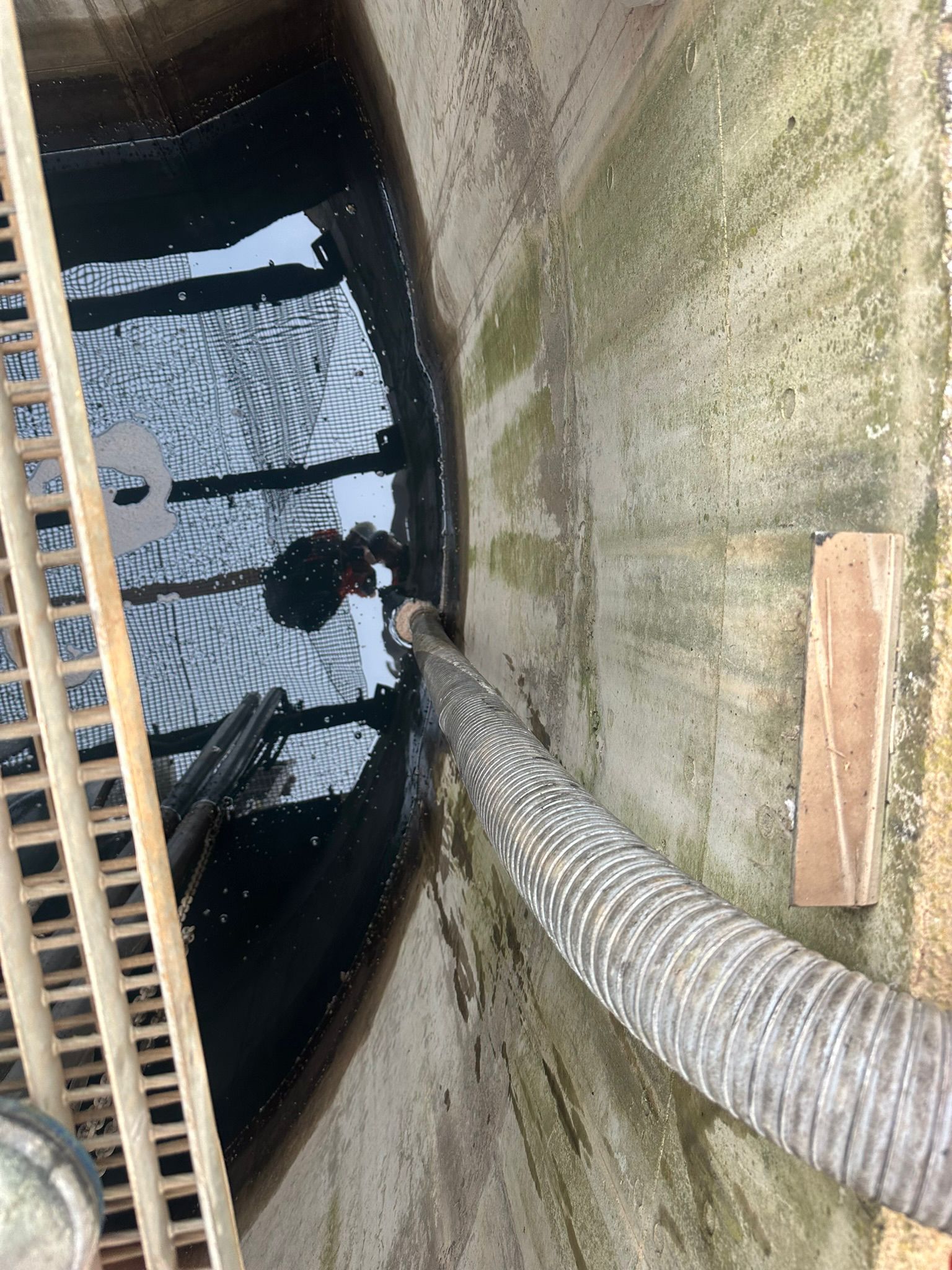 Interieur d'un bassin technique avec liquide sombre en cours d'aspiration