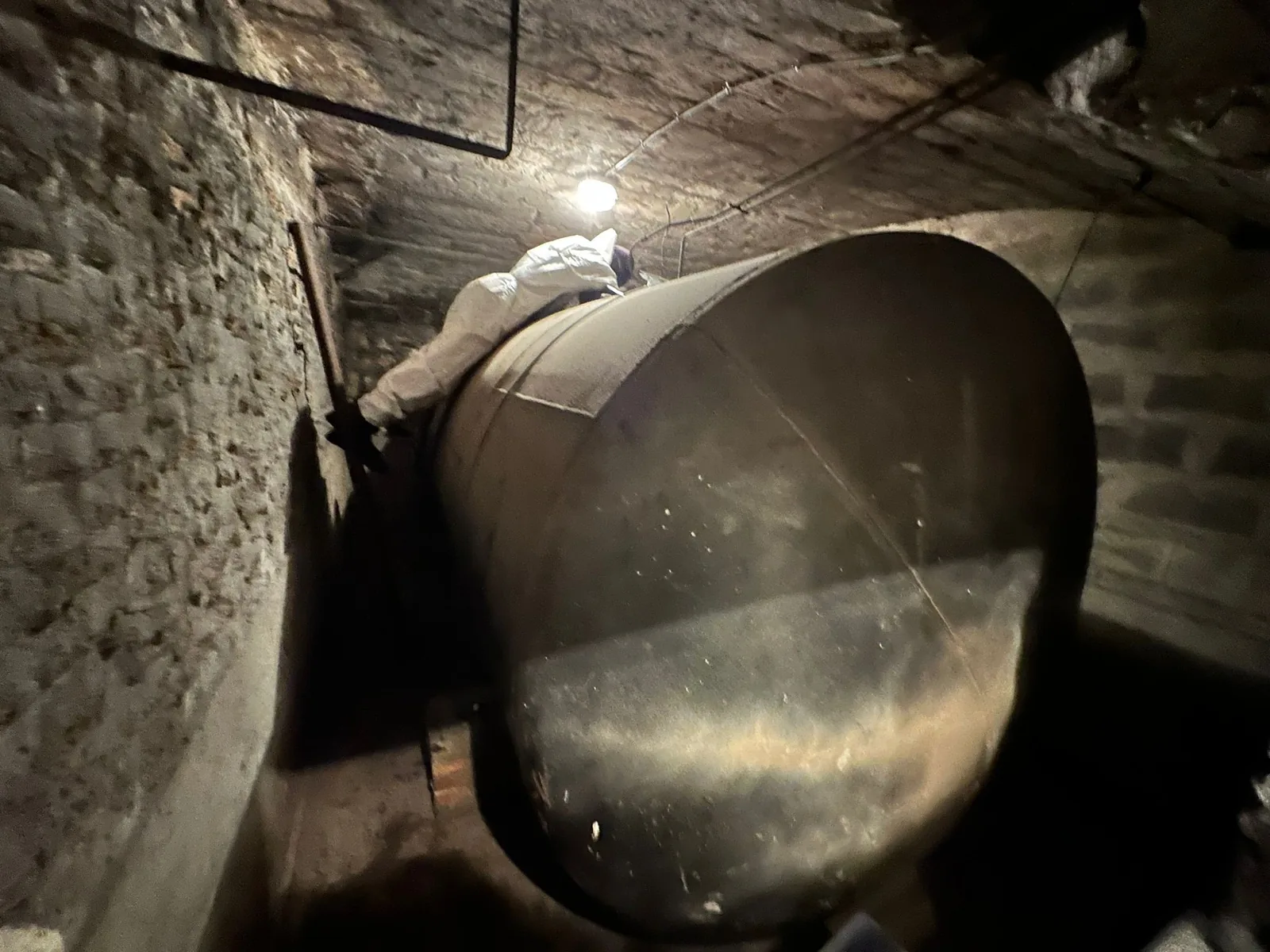 Technicien intervenant sur une cuve acier en cave lors d'une mise hors service