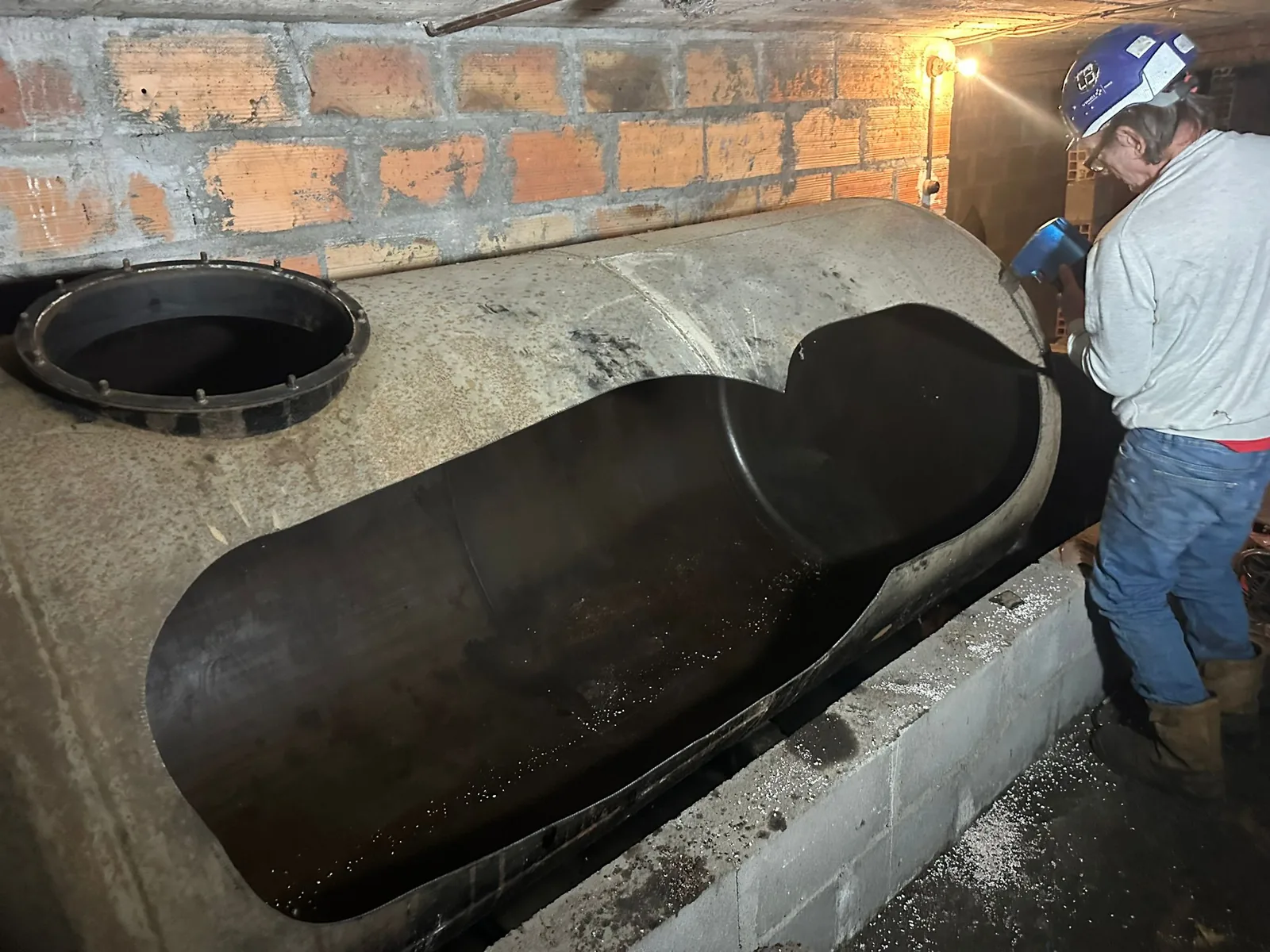 Grande ouverture découpée sur une cuve fioul en cave