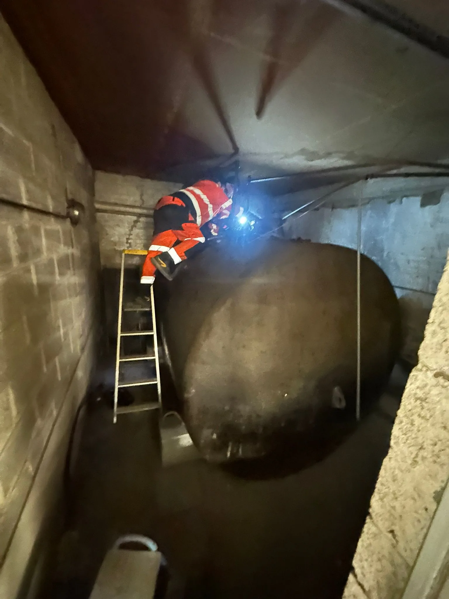 Technicien en intervention sur une cuve sous plafond bas dans une cave