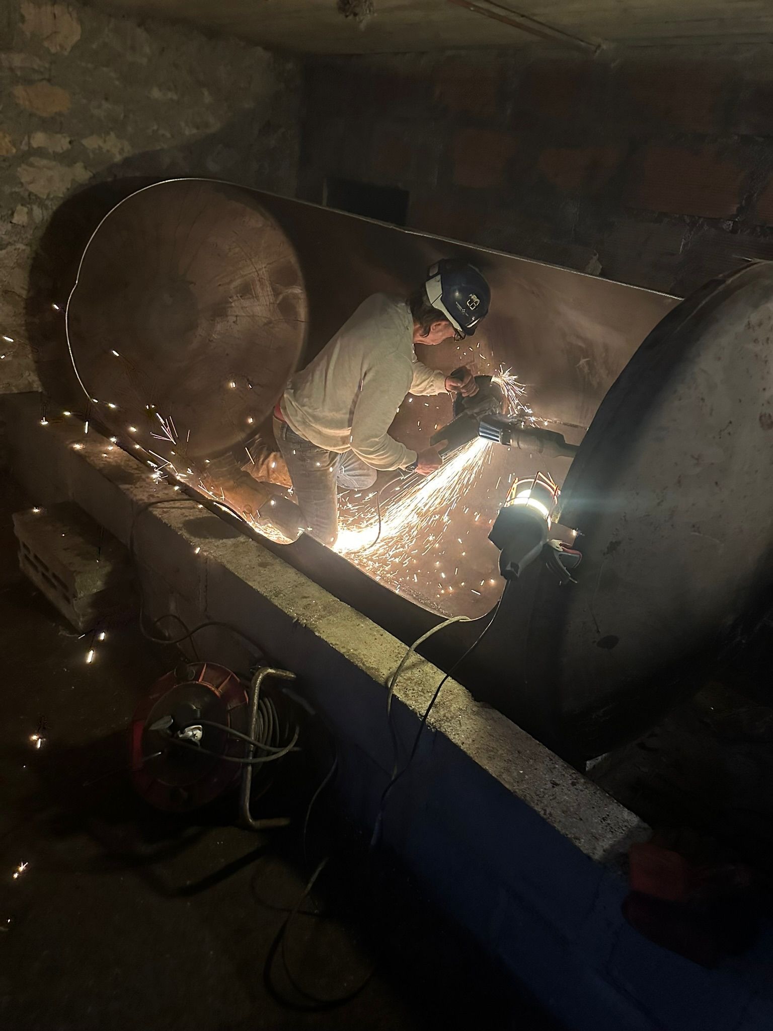 Découpe avec étincelles sur une cuve acier dans un local technique